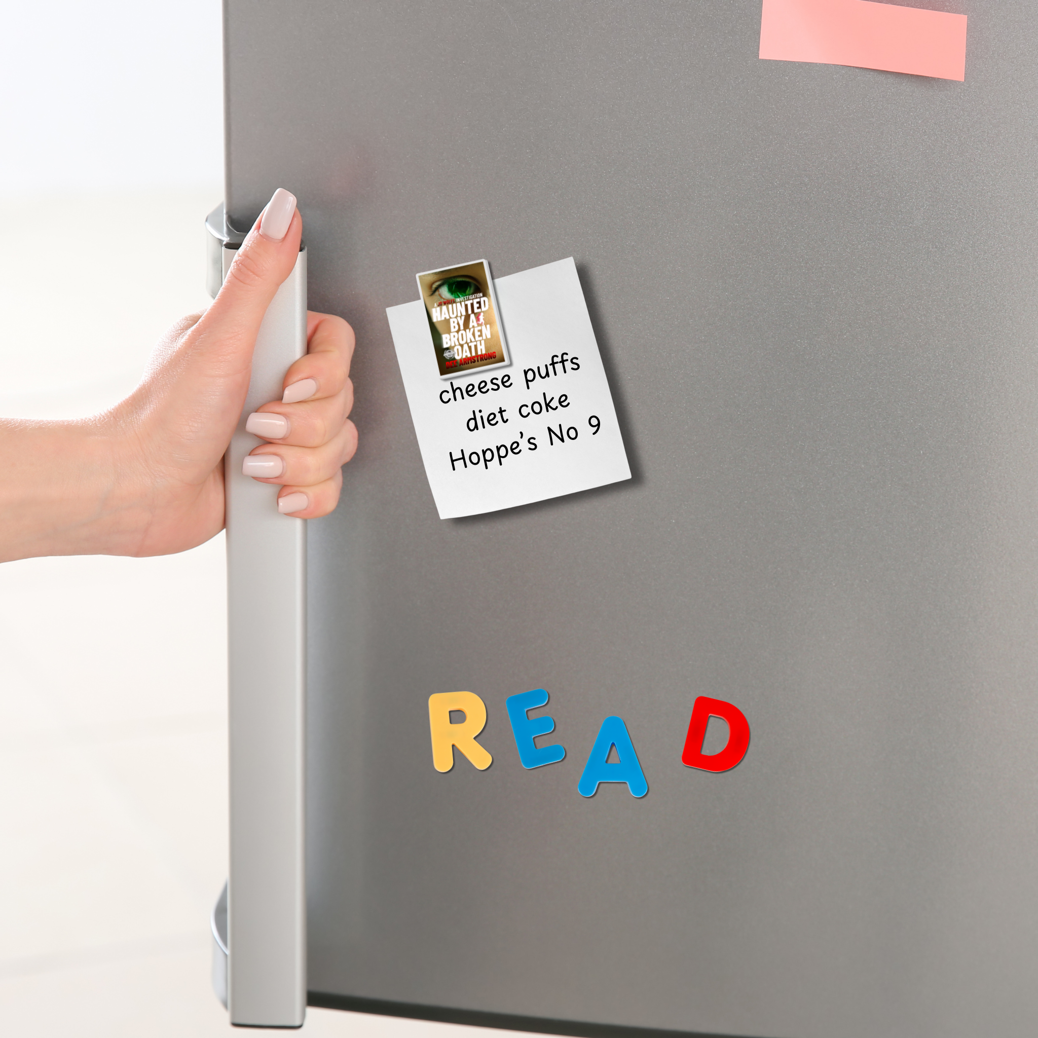 Hand holding a refrigerator handle with a Haunted by a Broken Oath magnet holding a note and colorful letters spelling 'READ' on a gray surface.