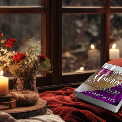 Book titled 'Haunted by Amethyst' on a red blanket with candles and flowers in the background.