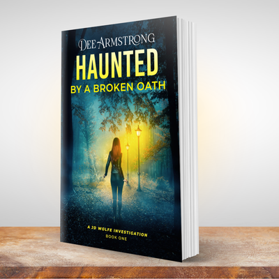 Book titled 'Haunted by a Broken Oath' by Dee Armstrong on a wooden surface with a blurred background